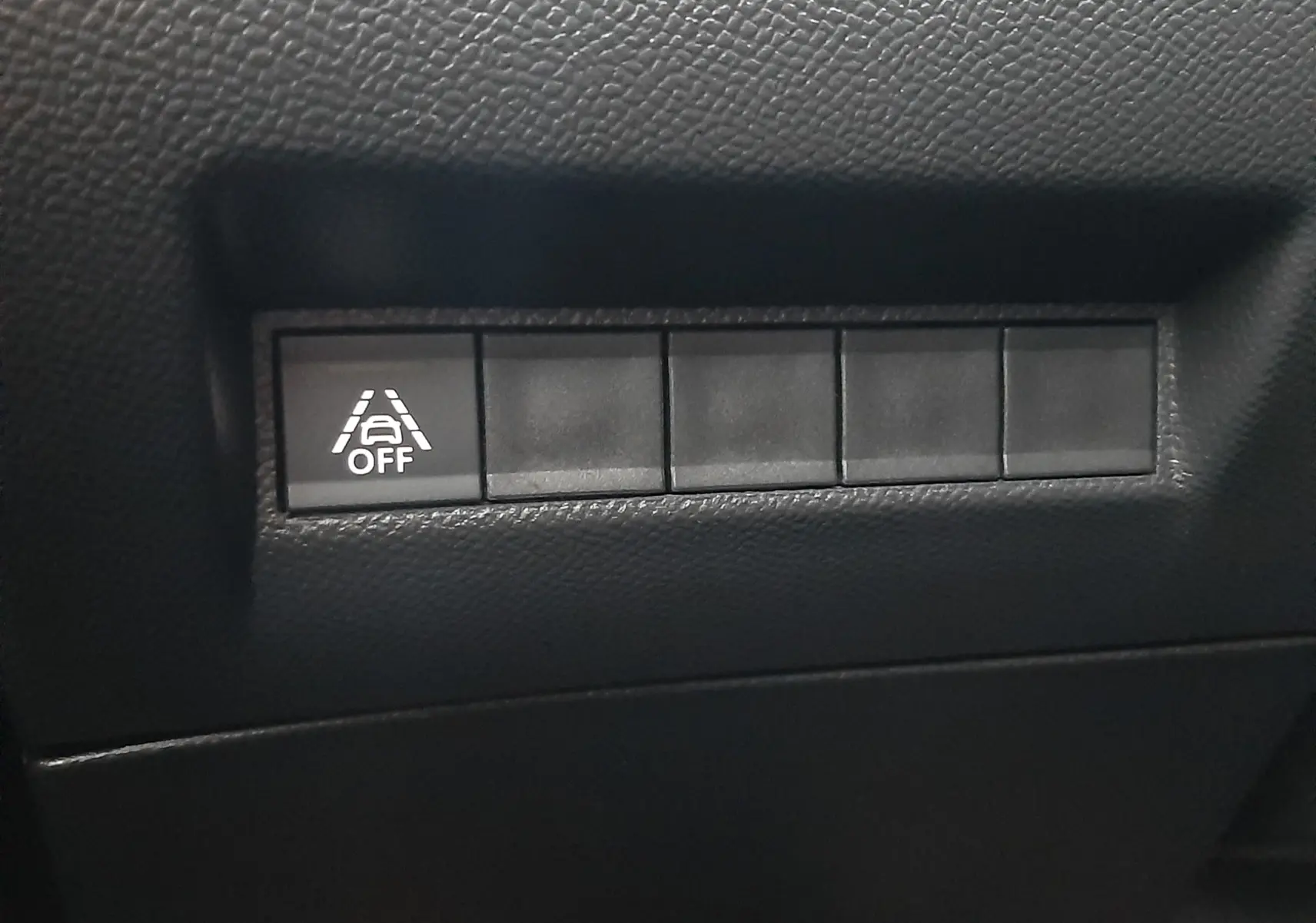 Bouton de désactivation de l'aide au maintien de voie sur tableau de bord noir du Peugeot 2008 blanc nacré 2023.