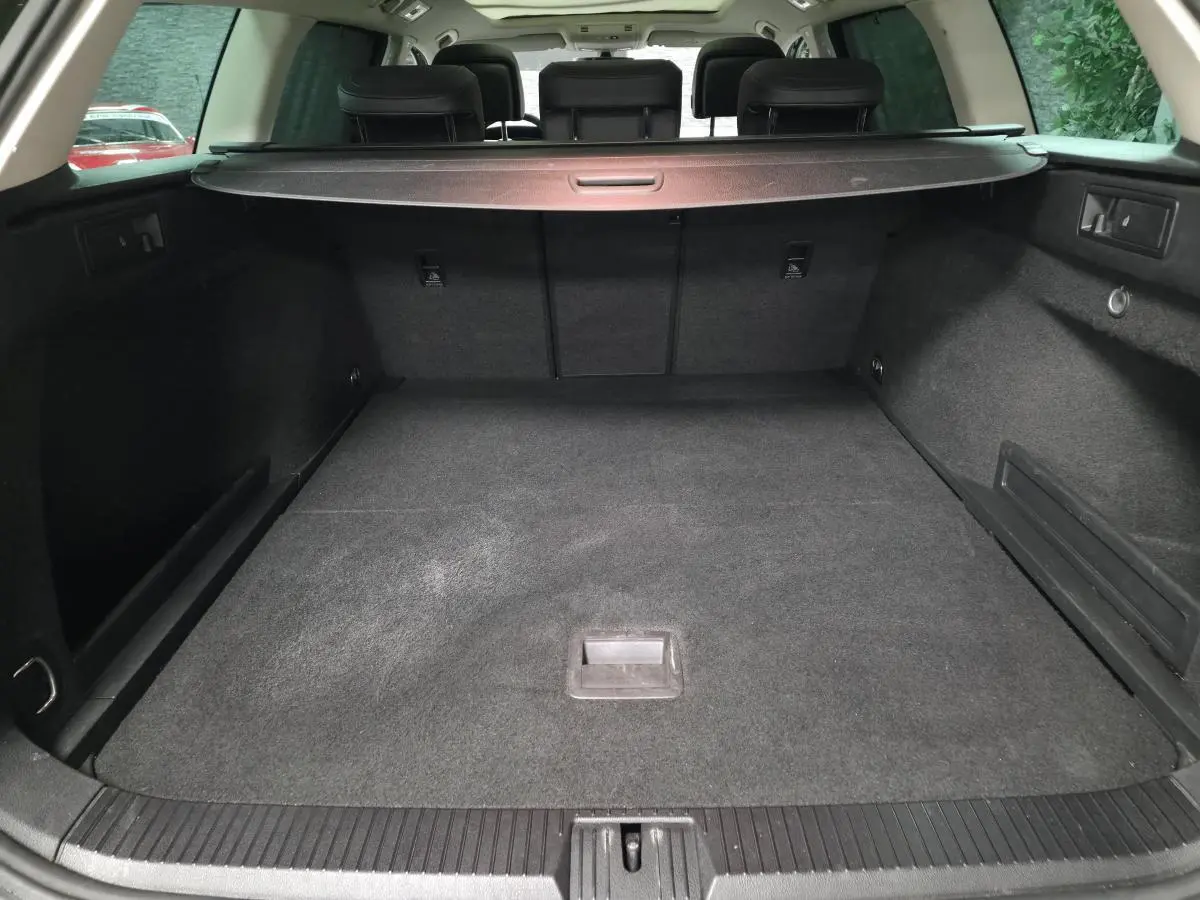 Coffre spacieux de Volkswagen Passat SW gris vu de l'arrière avec cache-bagages et banquette arrière noire.