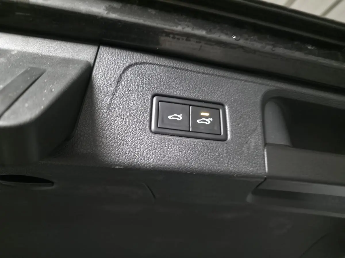 Boutons d'ouverture électrique du coffre et du hayon sur la partie intérieure du coffre d'une Volkswagen Passat SW gris.