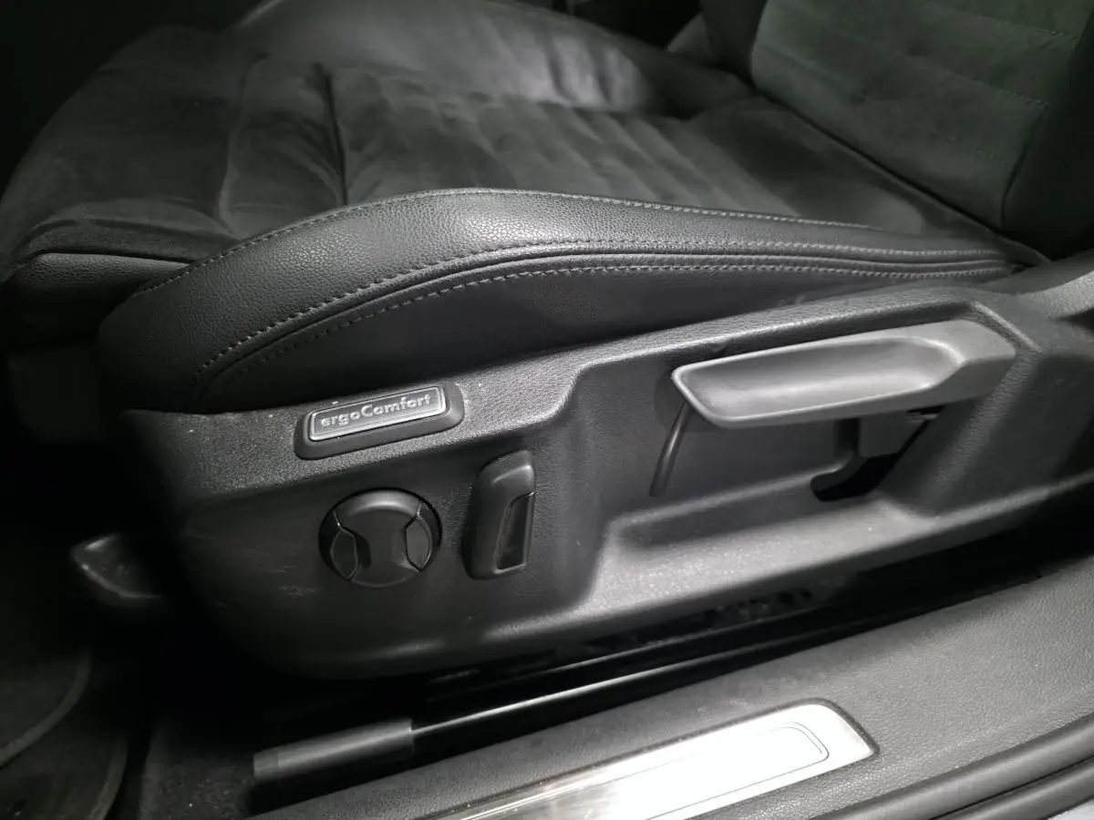 Gros plan sur les commandes de réglage du siège conducteur noir en cuir de la Volkswagen Passat SW Carat 2019.
