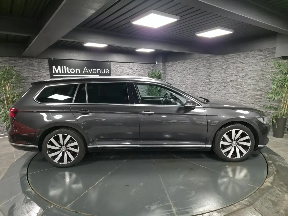 Profil droit d'une Volkswagen Passat SW gris métallisé avec jantes alliage 18 pouces Dartford dans un showroom intérieur.