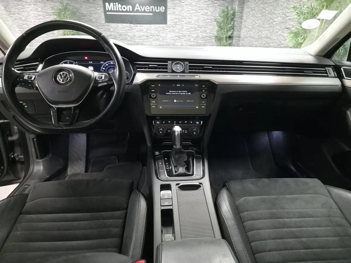 Vue intérieure avant de la Volkswagen Passat SW Carat 2019 avec tableau de bord noir et console centrale équipée d'un levier de vitesses automatique.