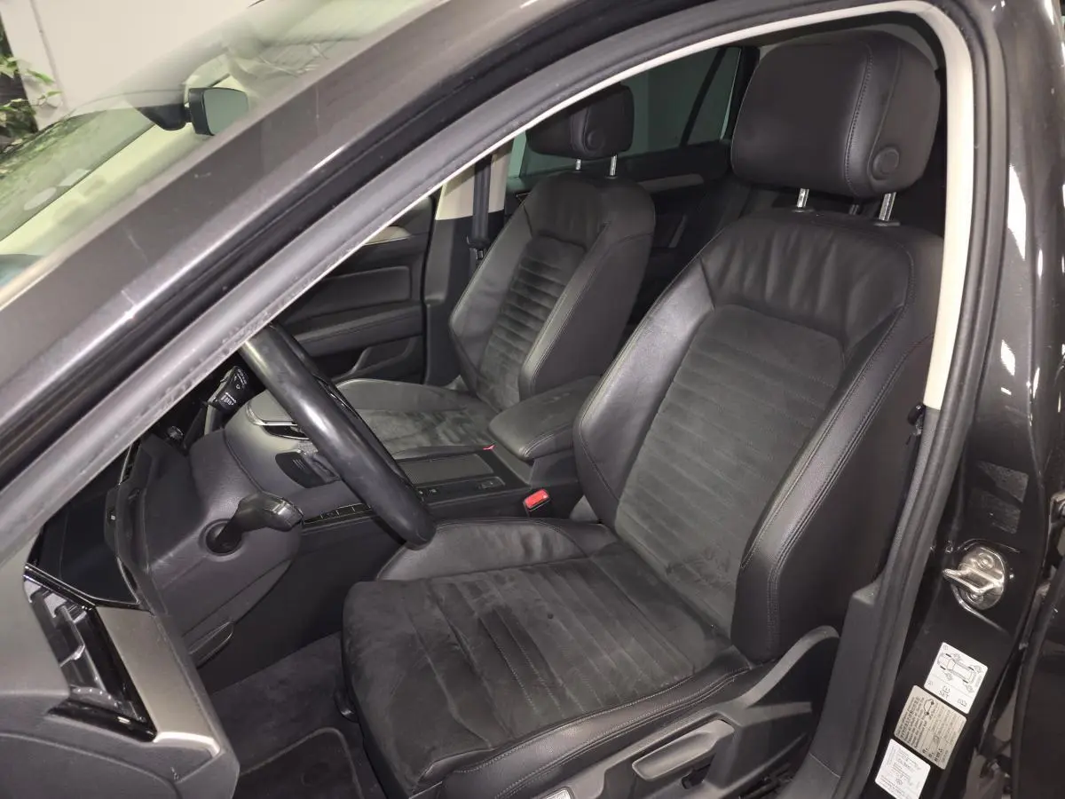 Vue intérieure côté conducteur de la Volkswagen Passat SW 2019 avec sièges en cuir noir et volant multifonction.