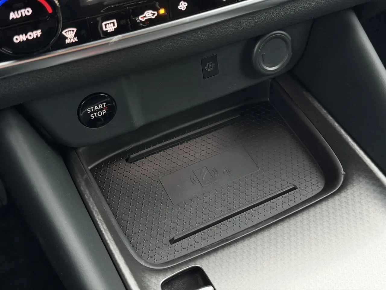 Gros plan sur la console centrale du Nissan Qashqai 2025, zone de charge sans fil et bouton Start/Stop noir.