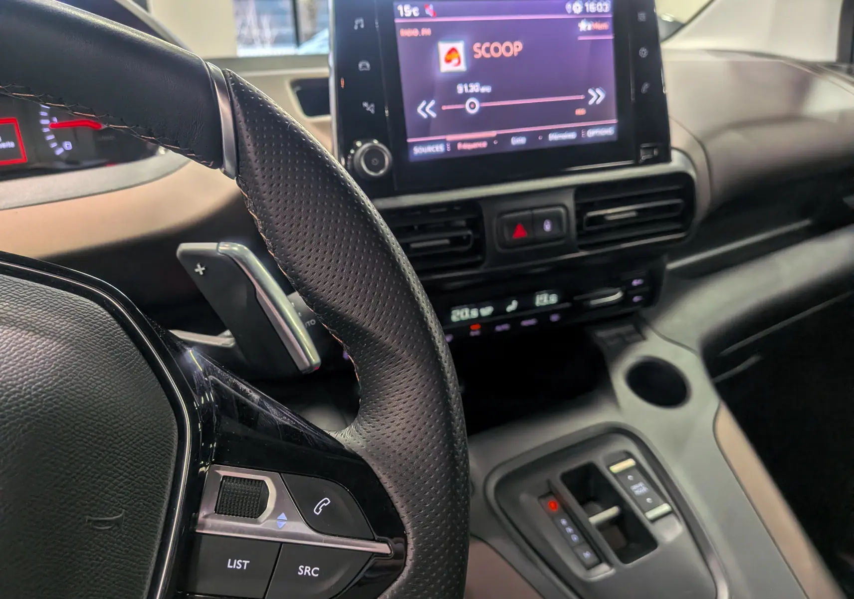Intérieur du Peugeot Rifter 2024 BlueHDi, vue rapprochée du volant à gauche et de l’écran tactile central affichant une radio.