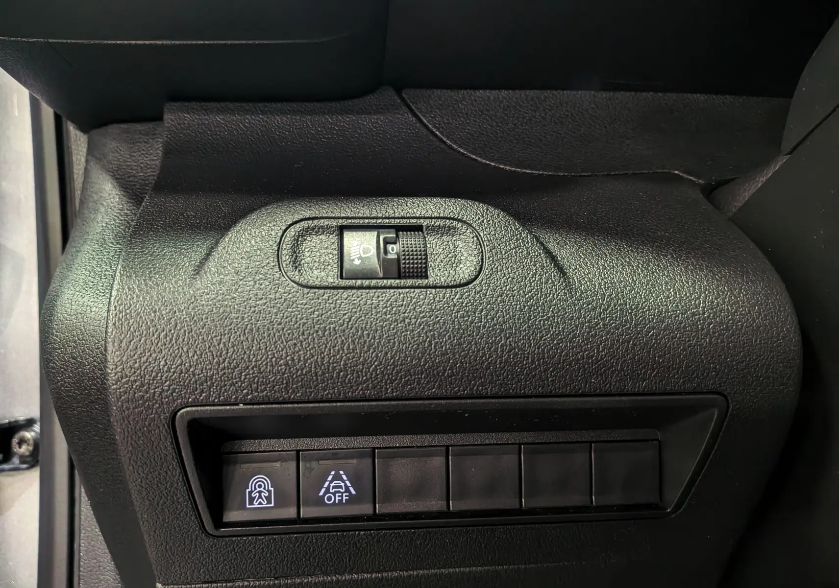 Vue rapprochée du tableau de bord côté gauche du Peugeot Rifter gris Artense, avec commandes d’éclairage et d’aide à la conduite.