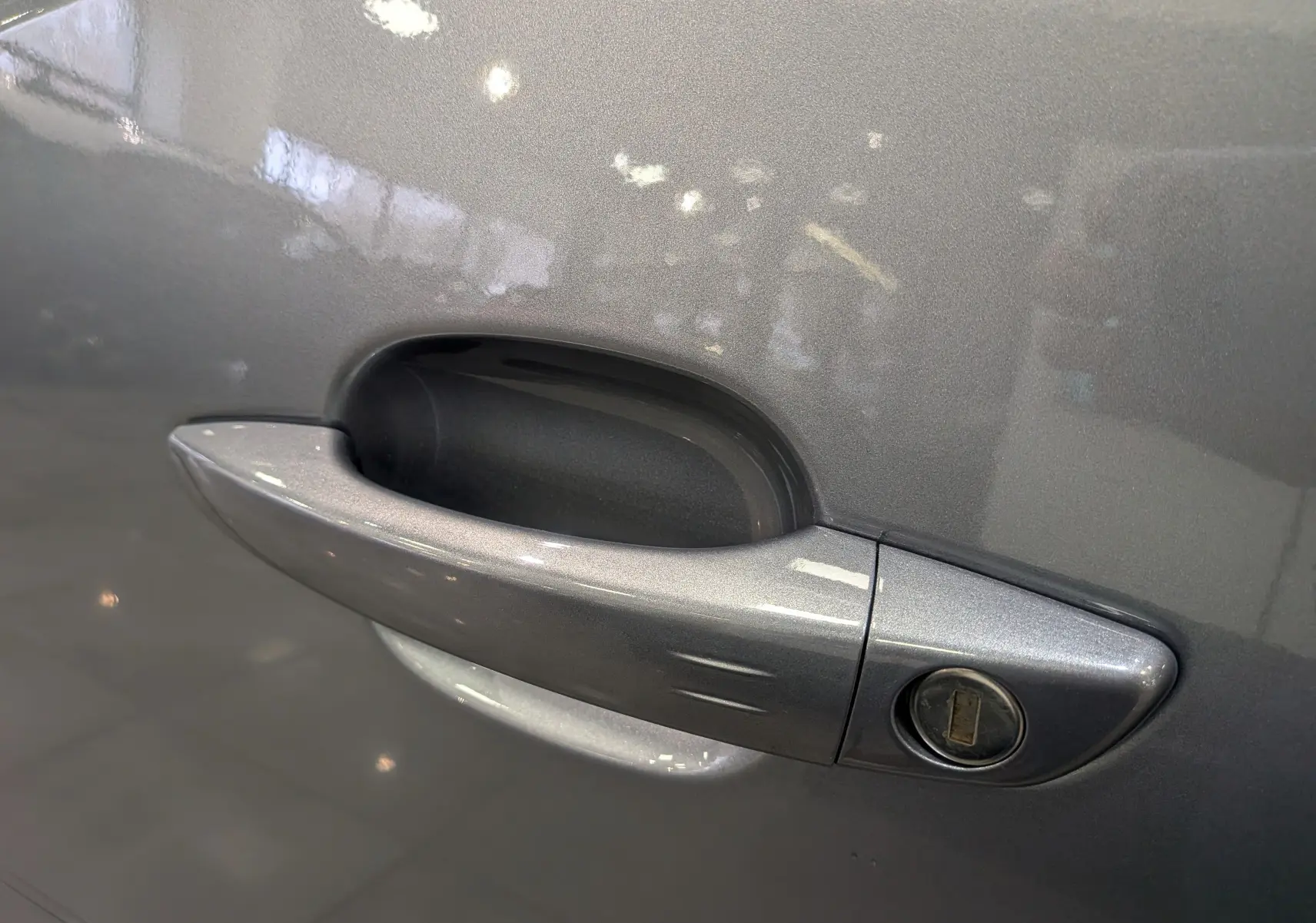 Poignée de porte côté gauche gris Artense du Peugeot Rifter 2024 BlueHDi 130 GT avec serrure visible en gros plan.