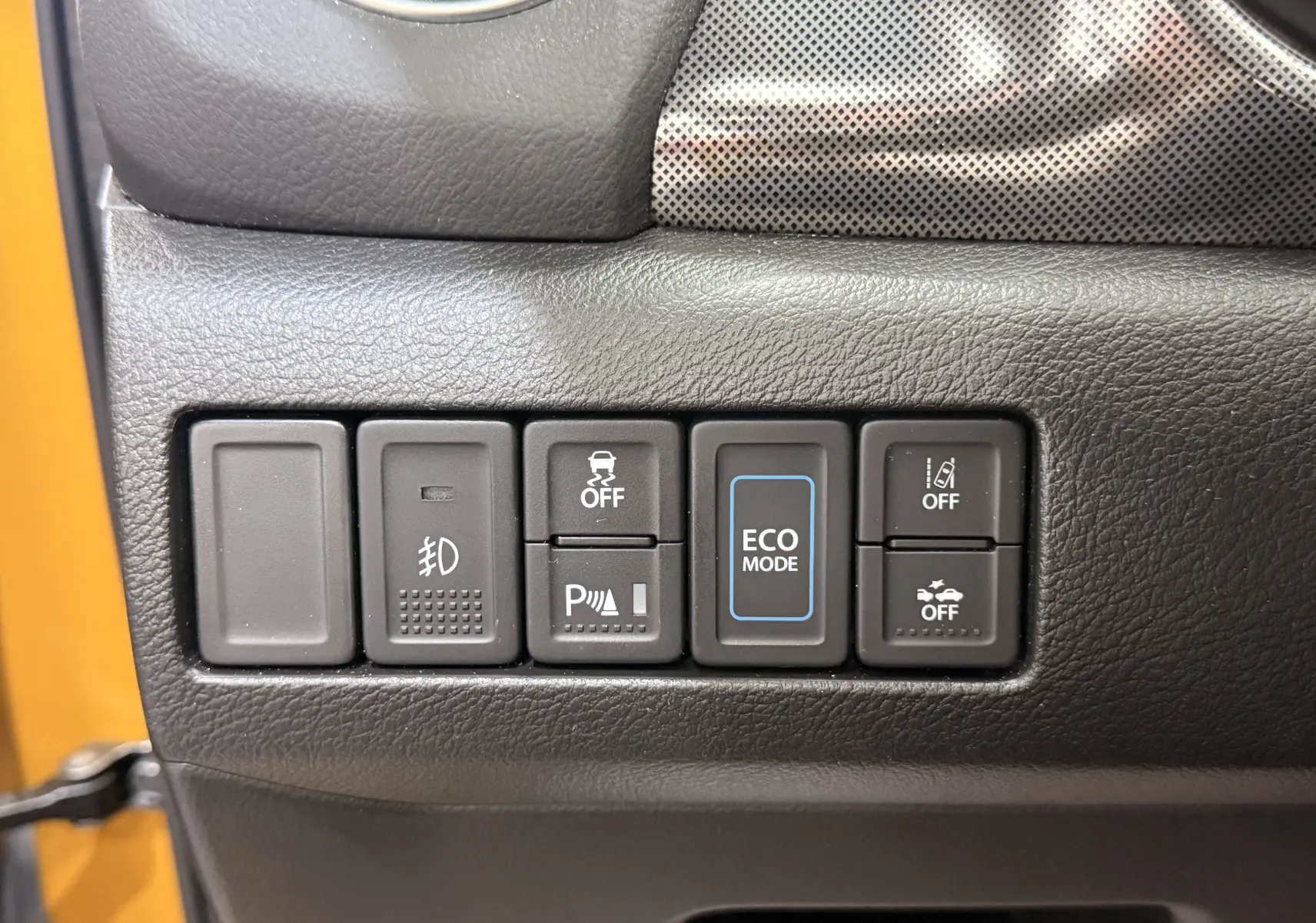 Gros plan sur les boutons de commande du tableau de bord du Suzuki Vitara jaune toit noir, avec mode ECO en surbrillance.
