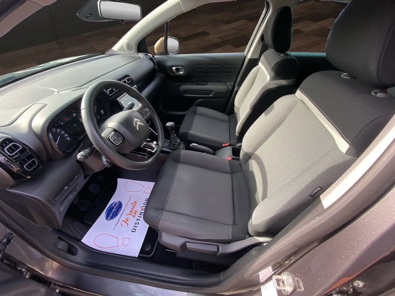 Vue intérieure côté conducteur de la Citroën C3 Aircross gris platinium, montrant les sièges tissu gris et le tableau de bord.