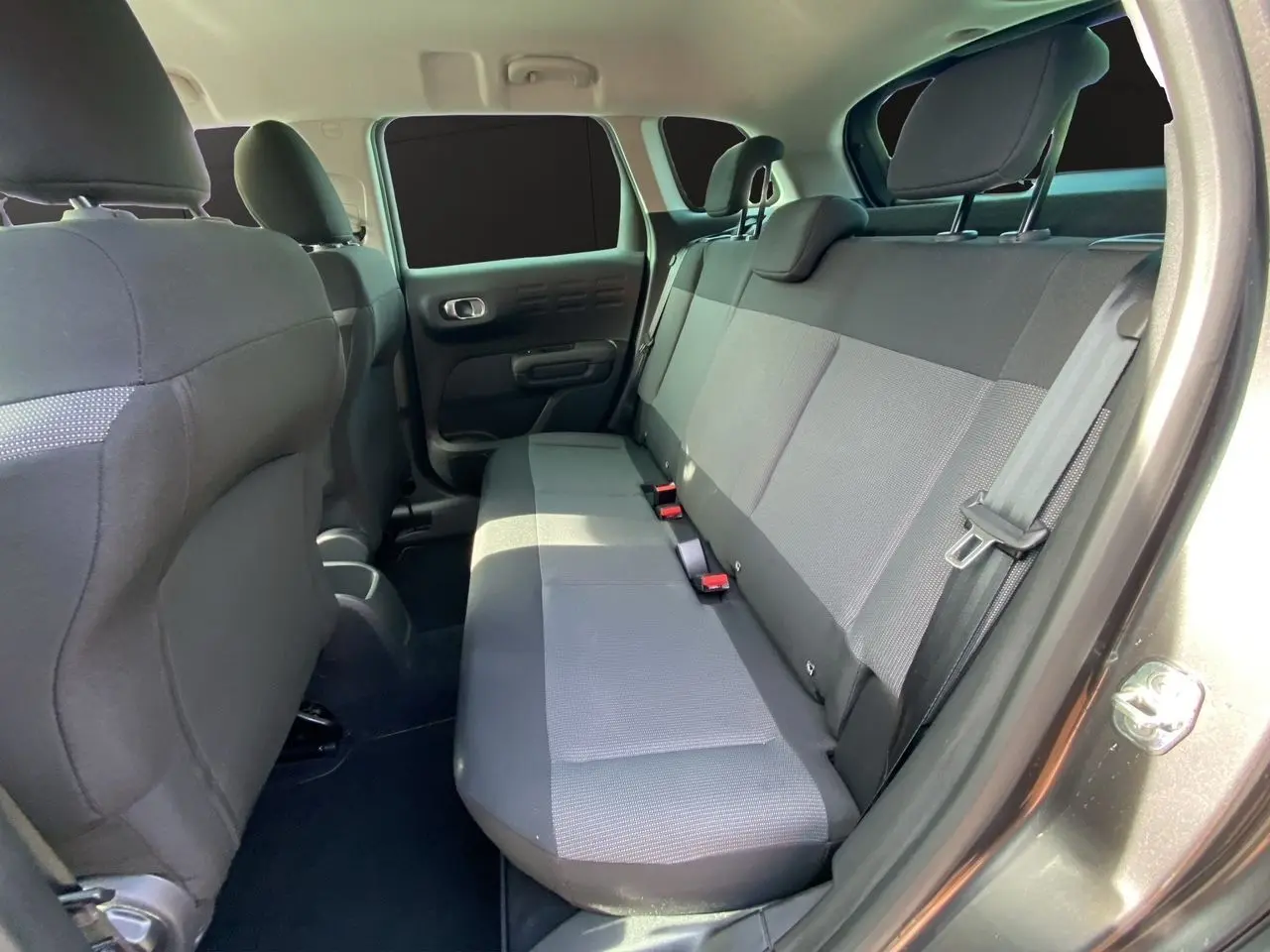 Vue intérieure du siège arrière côté droit du Citroën C3 Aircross gris platinium avec banquette tissu gris et ceintures visibles.