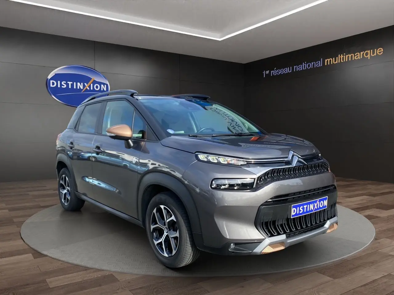 Vue 3/4 avant droit d'un Citroën C3 Aircross gris platinium avec détails cuivrés sur les rétroviseurs et la calandre.