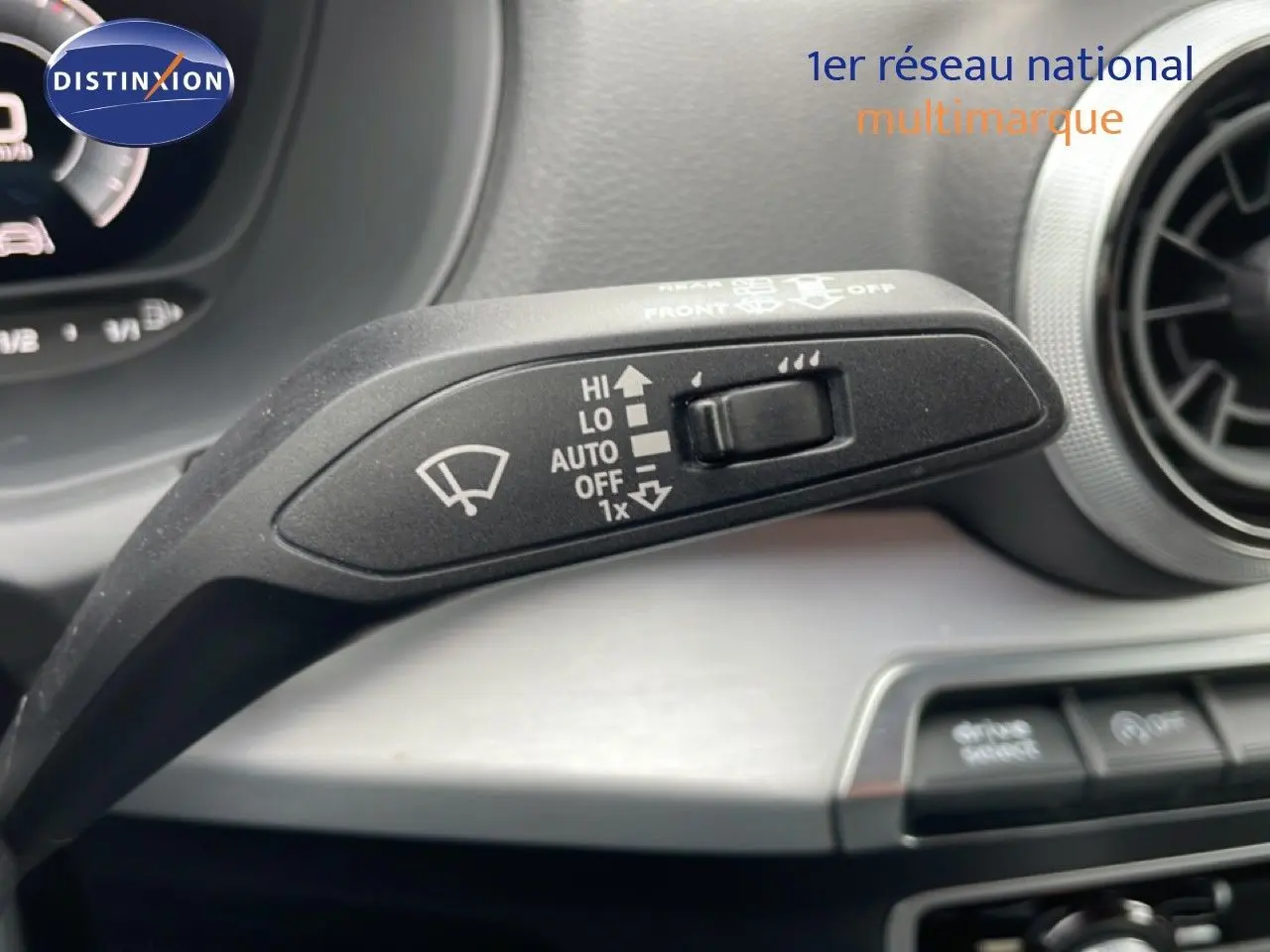 Gros plan sur la commande d’essuie-glace à gauche du volant dans l’Audi Q2 argent rose métal, tableau de bord en arrière-plan.