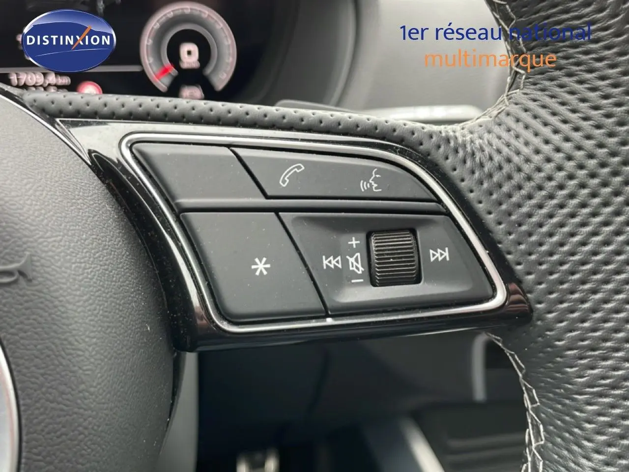 Gros plan sur les commandes noires du volant en cuir perforé de l'Audi Q2 35 2.0 TDI S-Line, intérieur noir.