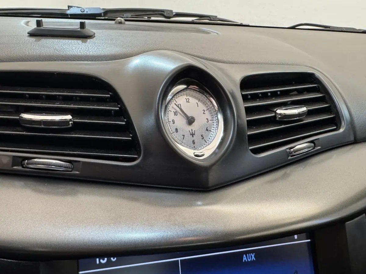Gros plan sur l'horloge centrale et les aérateurs noirs du tableau de bord gris foncé de la Maserati Granturismo S 4.7.