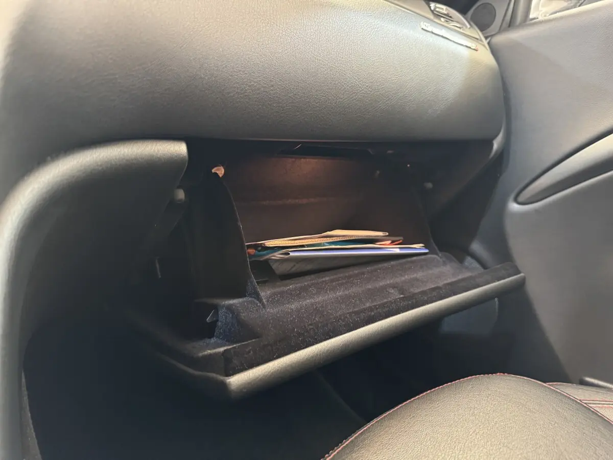Vue intérieure côté passager de la boîte à gants ouverte d'une Maserati Granturismo S 4.7 gris foncé avec documents à l'intérieur.
