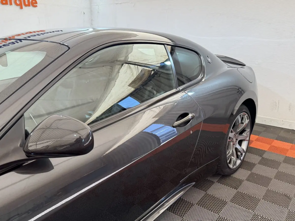Vue latérale droite d'une Maserati Granturismo S 4.7 gris foncé avec rétroviseur en carbone et jantes sport.