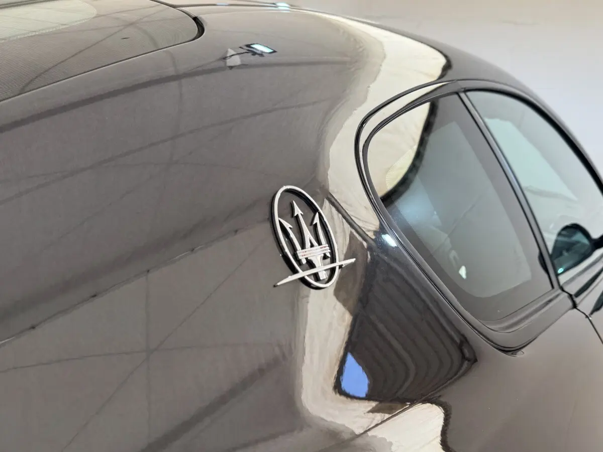 Vue rapprochée du côté gauche arrière d’une Maserati Granturismo S 4.7 gris foncé avec logo trident visible.