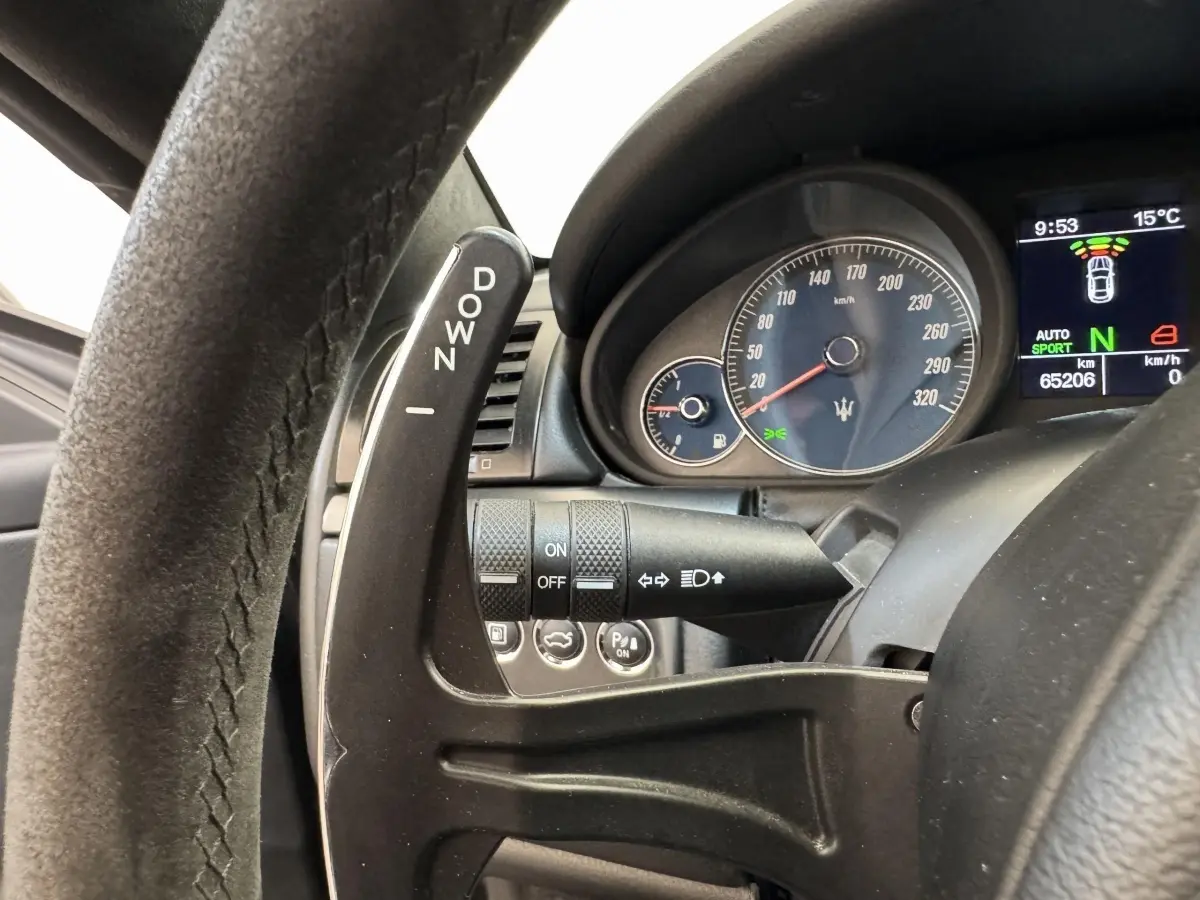 Gros plan sur le volant et le compte-tours bleu de la Maserati Granturismo S 4.7 gris foncé, avec palette de vitesse "DOWN".