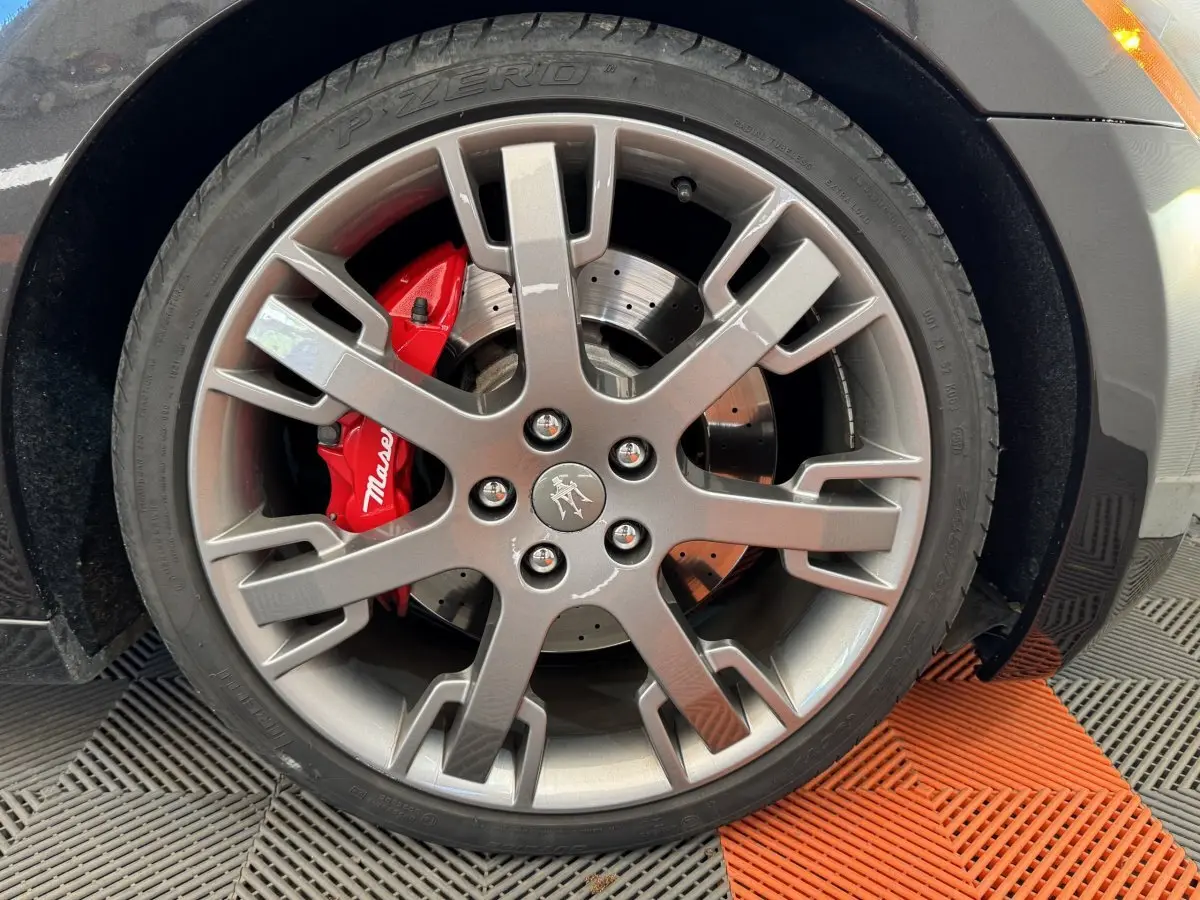 Gros plan sur la roue avant droite grise d'une Maserati Granturismo S 4.7 2010 avec étrier de frein rouge marqué Maserati.