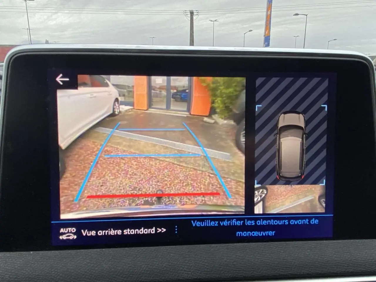 Écran de caméra de recul du Peugeot 3008 montrant la vue arrière avec lignes de guidage et vue 360° du véhicule.