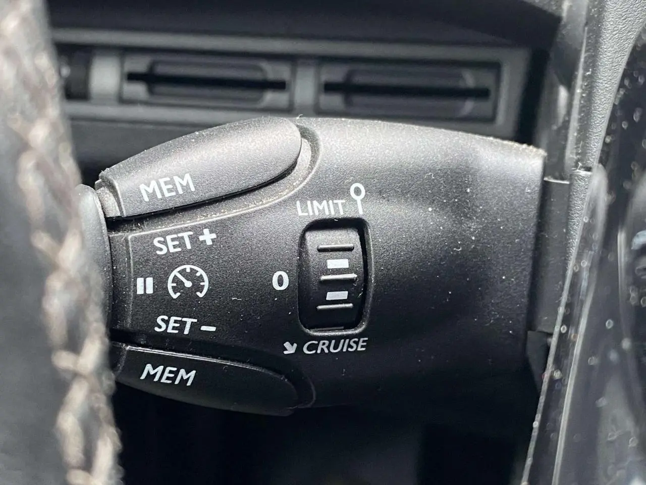 Gros plan sur la commande de régulateur de vitesse du Peugeot 3008, bouton noir avec inscriptions blanches.