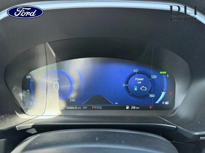 Tableau de bord numérique du Ford Kuga 2023 affichant la vitesse, la puissance et l'autonomie, éclairage bleu.