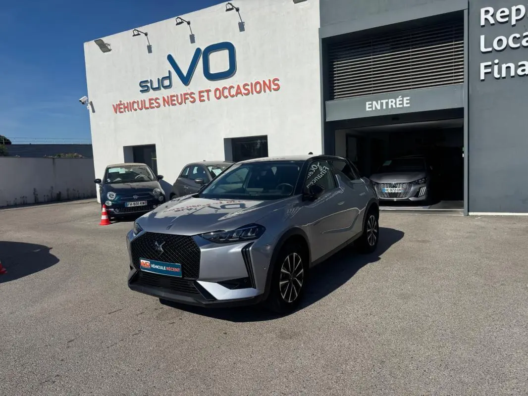 DS3 100 BVM6 Bastille gris 2024 en 3/4 avant droit, avec jantes alliage 18 pouces, stationné devant un garage sud VO.