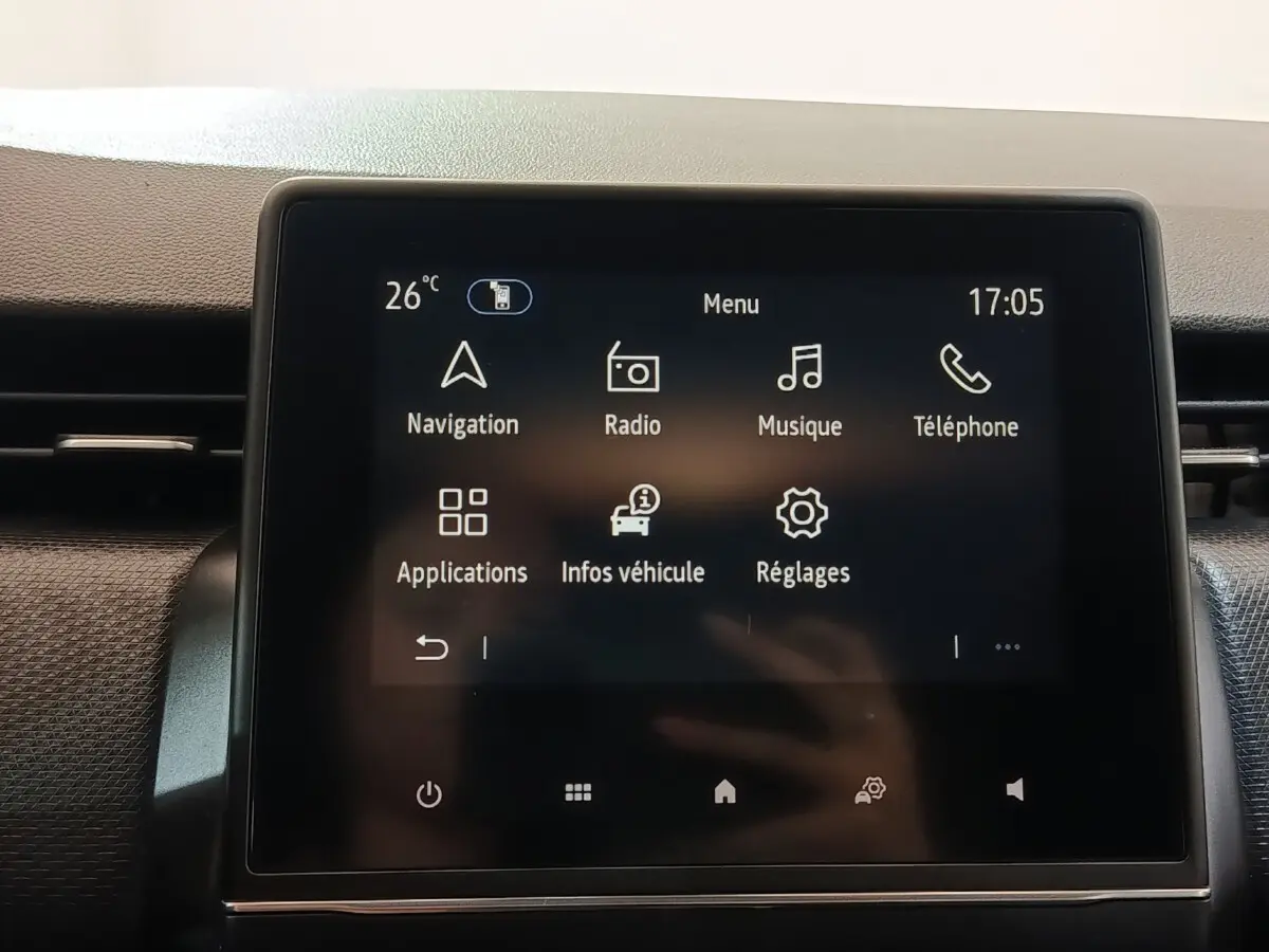 Écran tactile central de la Renault Clio Business E-TECH 140 blanc, affichant le menu principal avec navigation et radio.