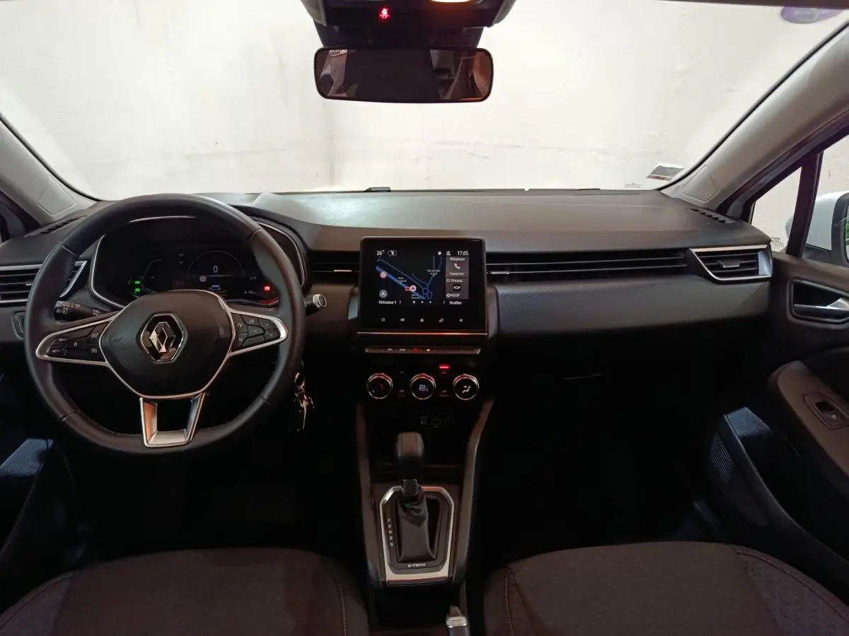 Vue intérieure avant de la Renault Clio Business E-TECH 140 2021, tableau de bord noir avec écran tactile central et volant multifonctions.