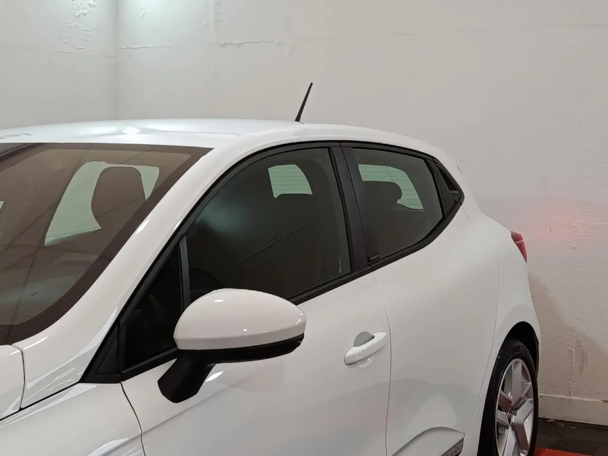 Vue de profil côté gauche d'une Renault Clio Business E-TECH blanche avec rétroviseur et poignée de porte visibles.