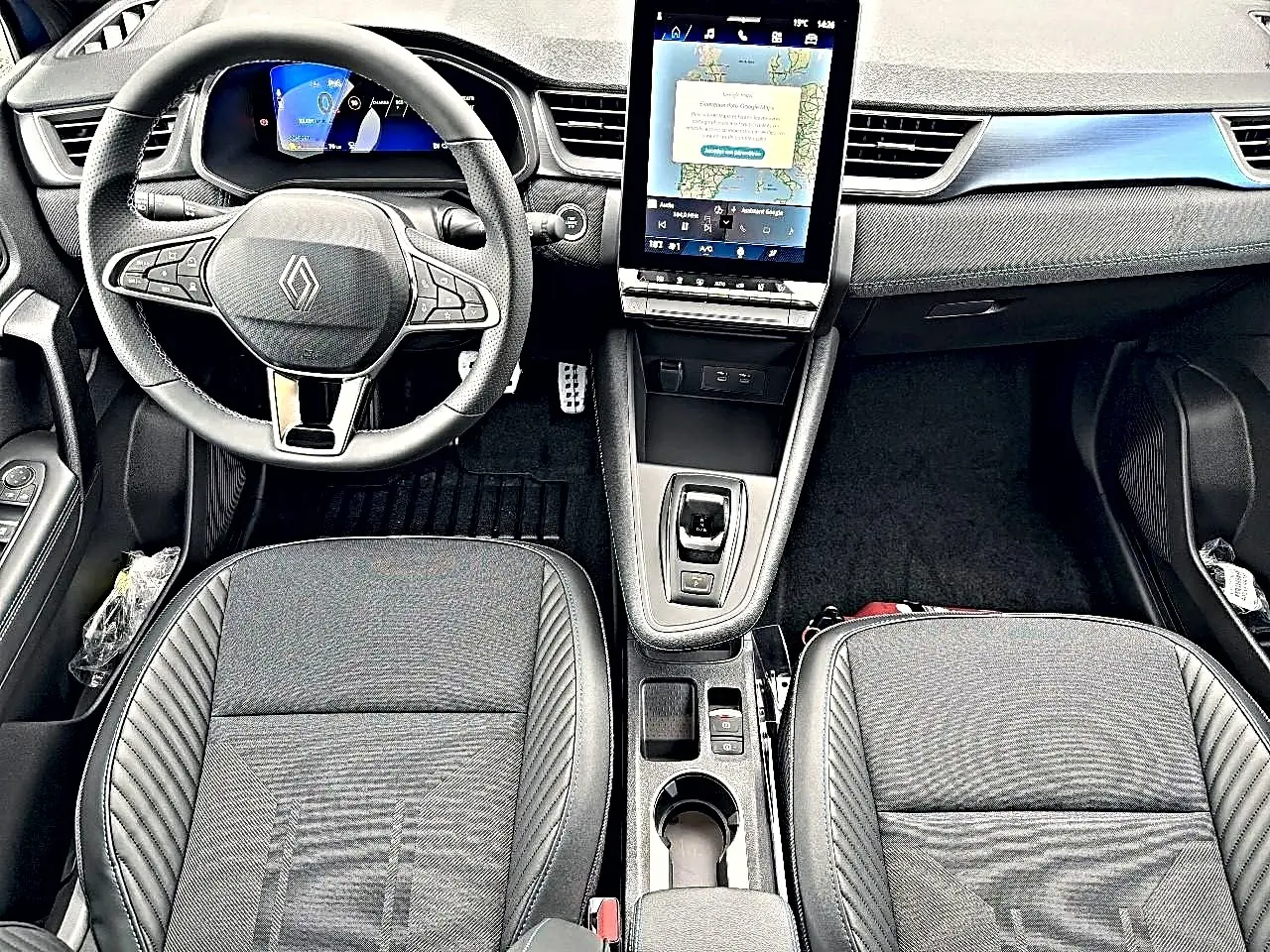 Vue intérieure frontale du tableau de bord et des sièges noirs du Renault Symbioz 2026 avec écran tactile vertical et volant multifonction.