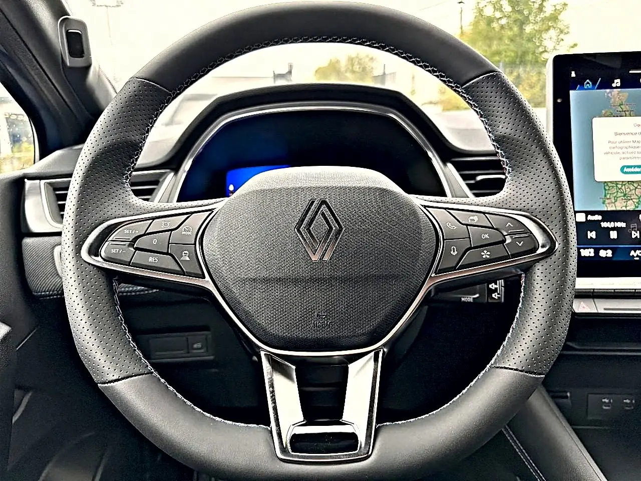 Vue rapprochée du volant multifonction noir de la Renault Symbioz 2026 avec logo central et écran tactile à droite.