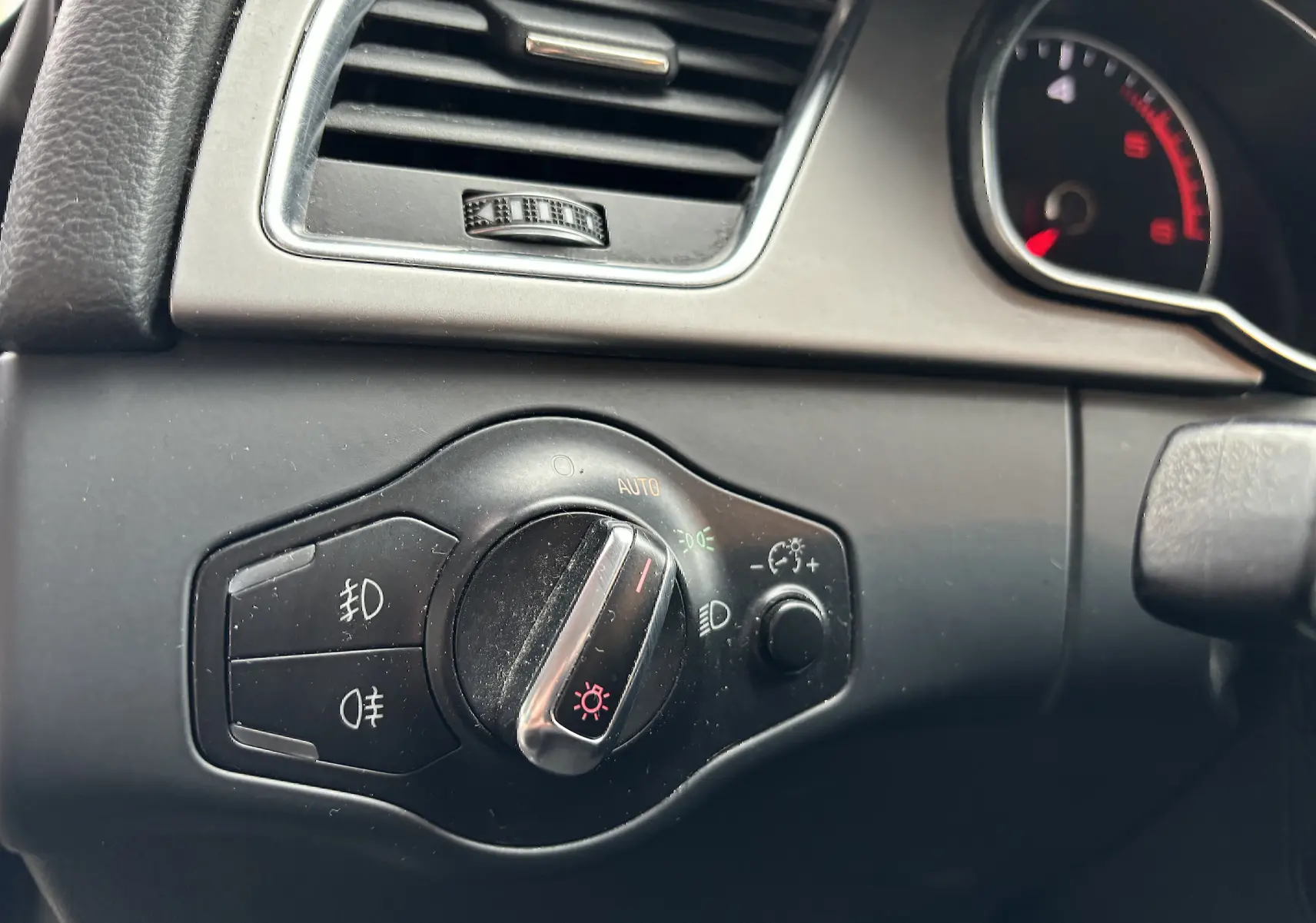 Gros plan sur le bouton de commande des phares et la ventilation du tableau de bord d'une Audi A5 Sportback noire de 2013.