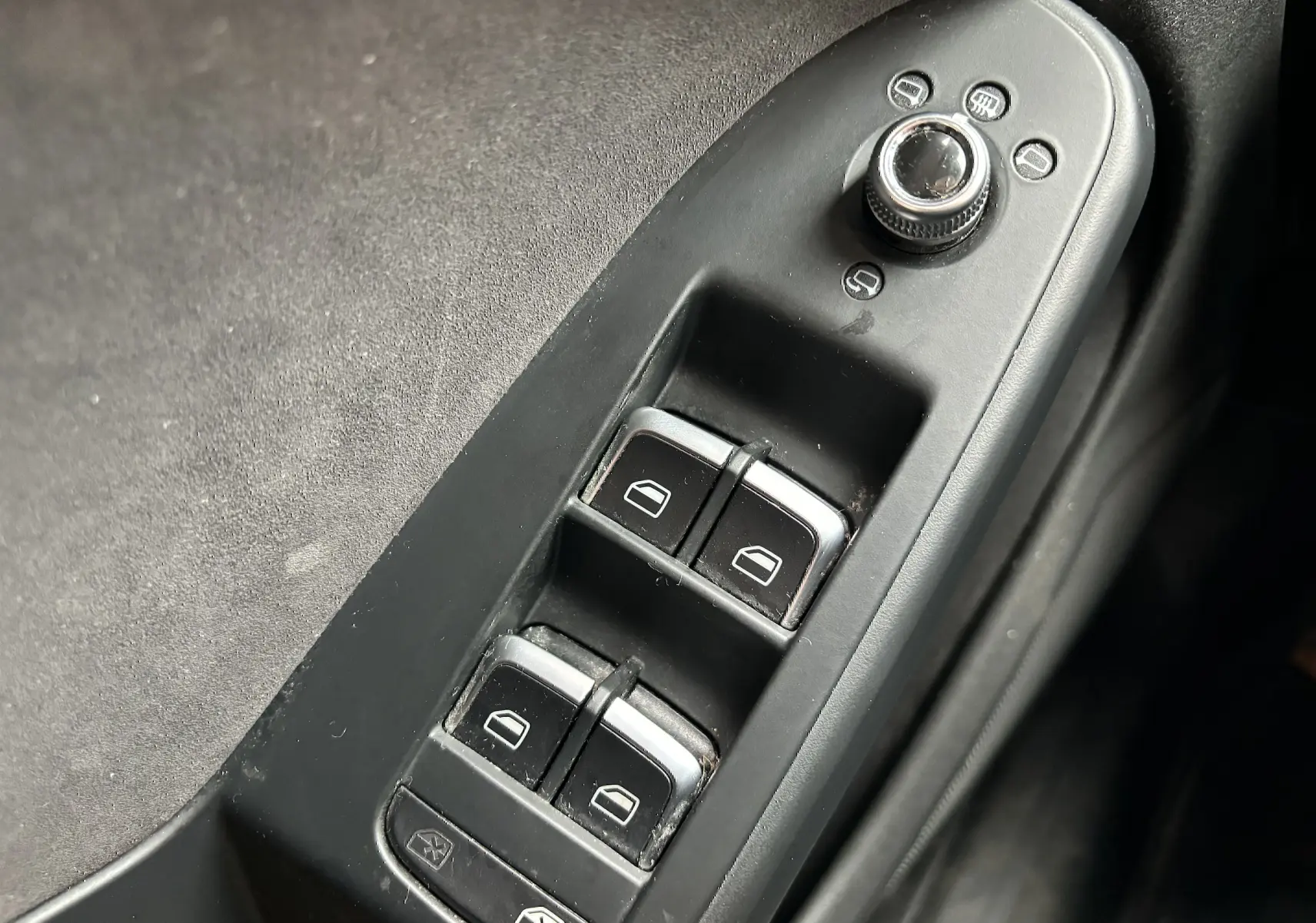 Gros plan sur les commandes de lève-vitres et réglage des rétroviseurs côté conducteur d'une Audi A5 Sportback noire de 2013.