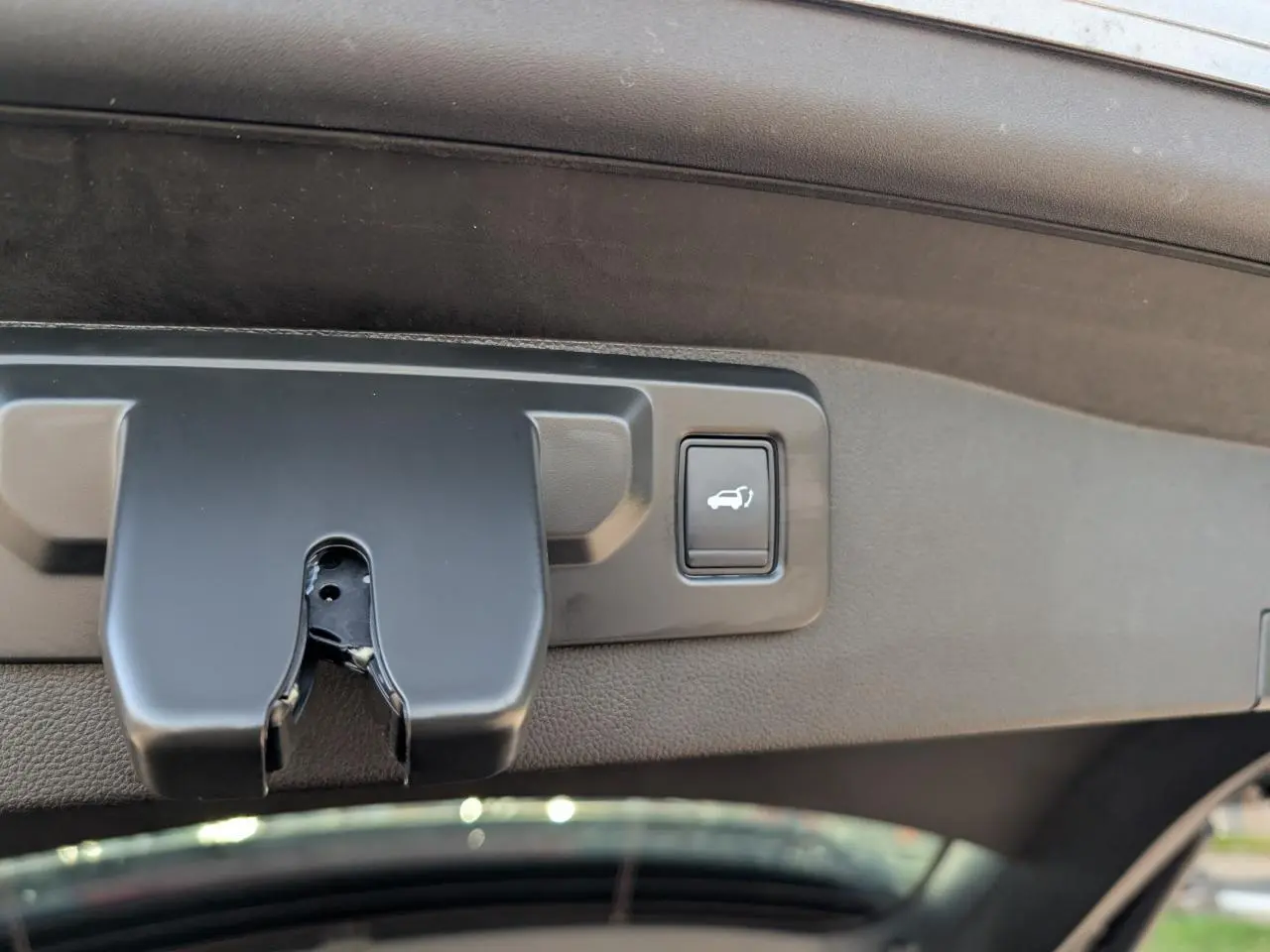 Détail du bouton d'ouverture électrique du hayon sur la partie intérieure du coffre du Renault Austral gris métallisé.