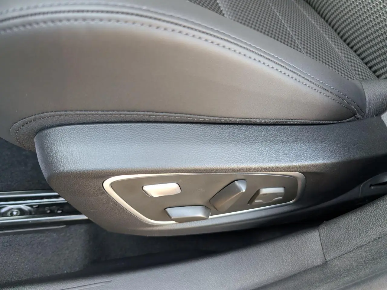 Gros plan sur les commandes électriques du siège conducteur en sellerie mixte tissu carbone Alcantara gris du Renault Austral 2025.