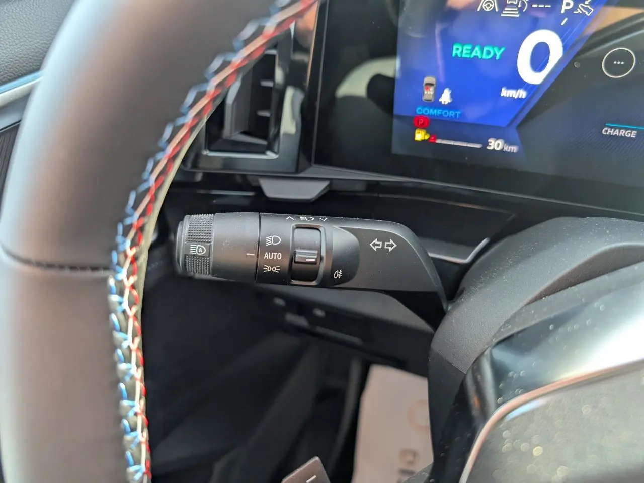 Gros plan sur la commande de clignotants à gauche du volant avec surpiqûres tricolores du Renault Austral gris métallisé.