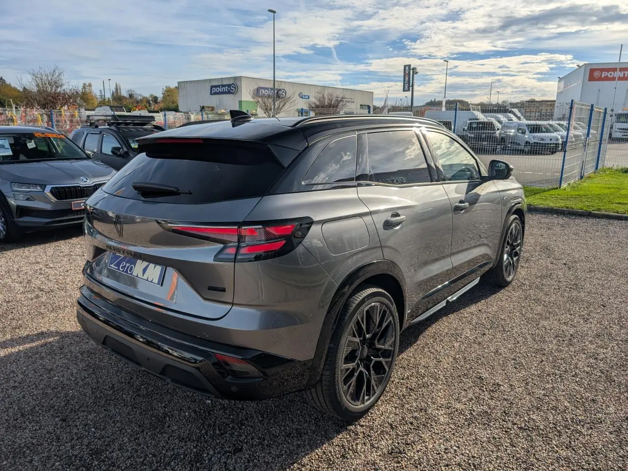 Vue 3/4 arrière droite d’un Renault Austral gris métallisé avec toit noir étoilé et jantes alliage noires.