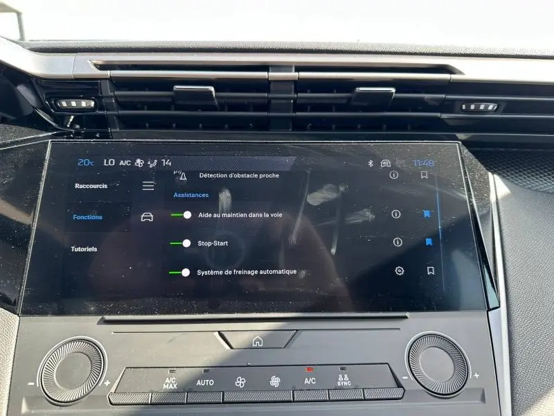 Vue rapprochée de l’écran tactile central de la Peugeot 308 bleu, affichant les aides à la conduite activées.