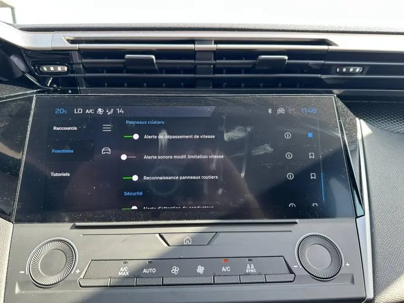 Vue rapprochée de l'écran tactile central et de la console de climatisation d'une Peugeot 308 bleu, version 2025.