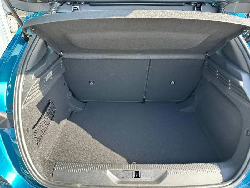 Coffre ouvert vu de l'arrière d'une Peugeot 308 bleu, montrant un espace de chargement propre et bien agencé.