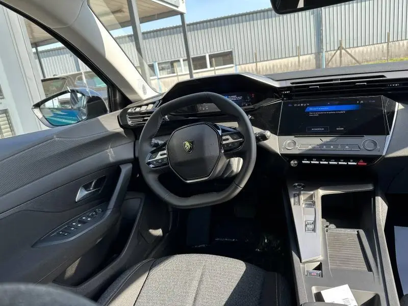 Vue intérieure avant gauche du poste de conduite de la Peugeot 308 2025 avec volant compact et écran tactile central.