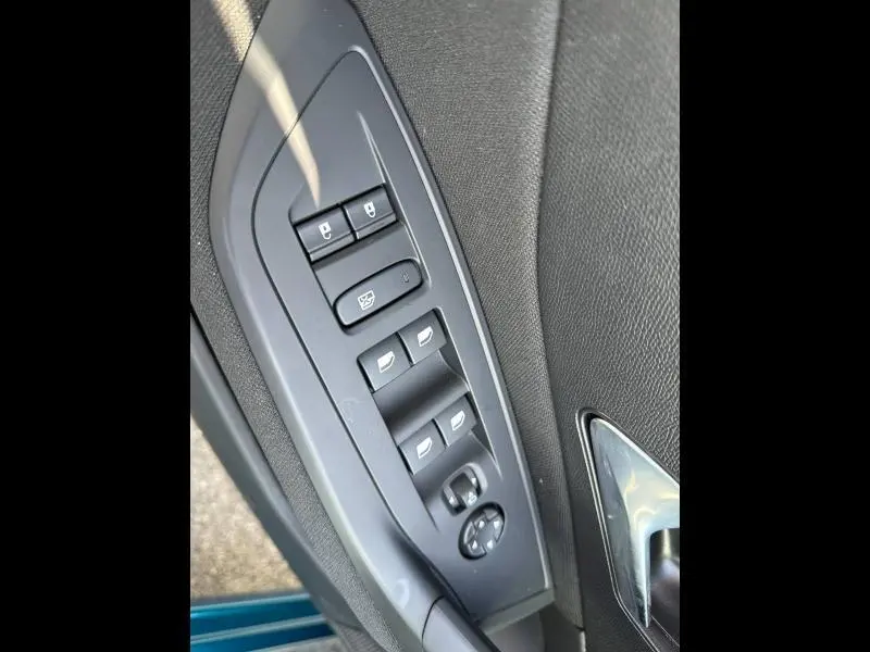 Vue en plongée sur les commandes de lève-vitres et verrouillage côté gauche d'une Peugeot 308 bleu 2025.
