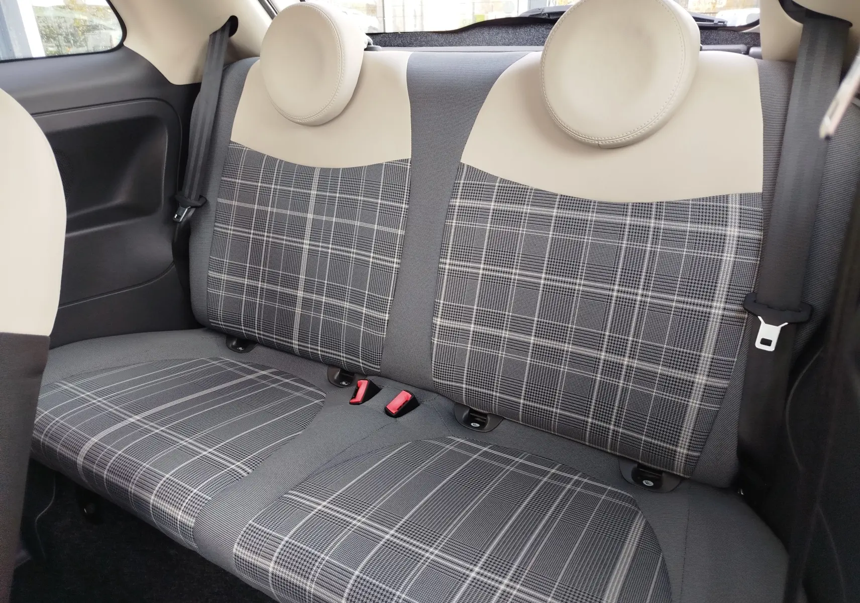 Vue rapprochée des sièges arrière en tissu à motif écossais gris et beige d'une Fiat 500 Lounge blanche.