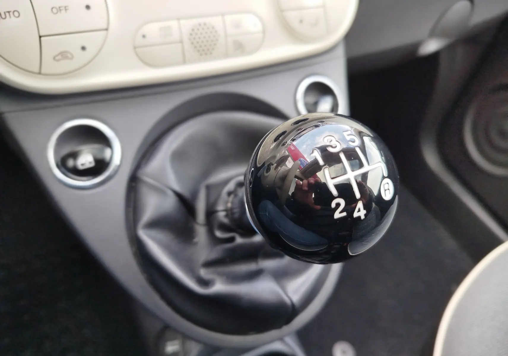 Gros plan sur le levier de vitesses manuel noir brillant de la Fiat 500 Lounge 2017 en intérieur beige.