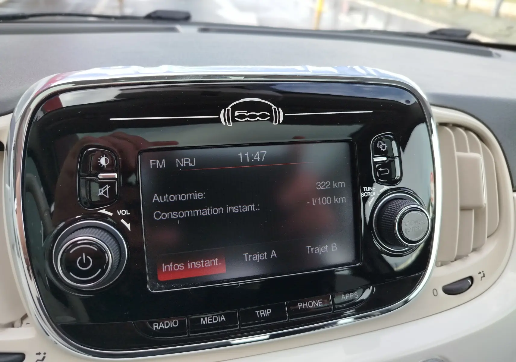 Vue rapprochée de l’écran multimédia noir brillant du tableau de bord de la Fiat 500 blanche, affichant les infos de trajet.