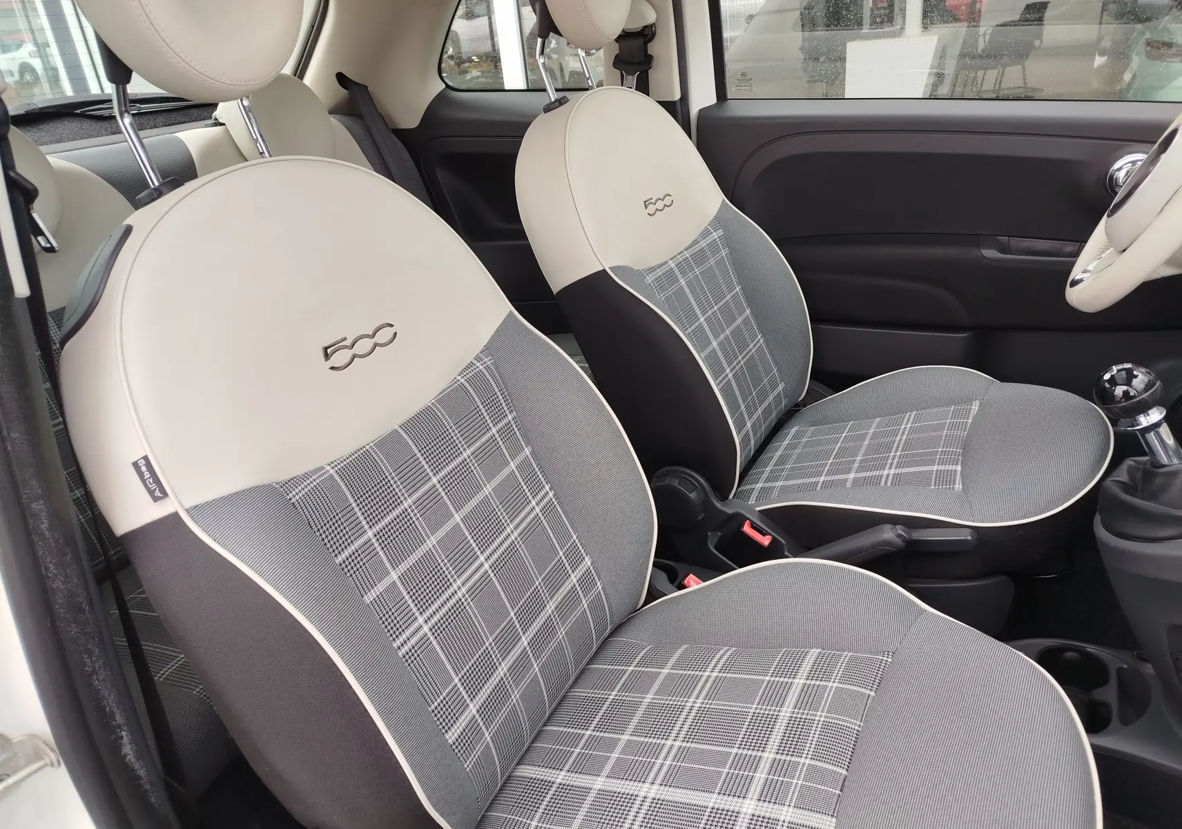 Vue intérieure côté conducteur de la FIAT 500 Lounge 2017, sièges tissu gris à motif écossais avec logo 500 brodé.