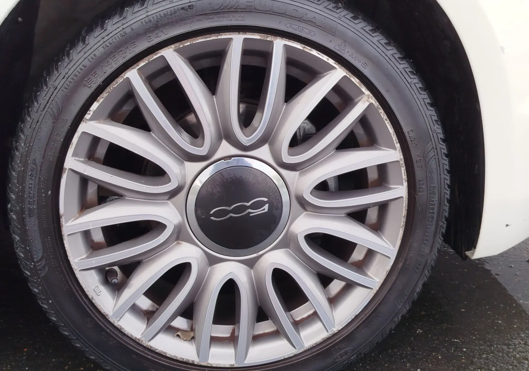 Gros plan sur la jante argentée en alliage de la FIAT 500 Bossa Nova White Pastel, avec logo central distinctif.