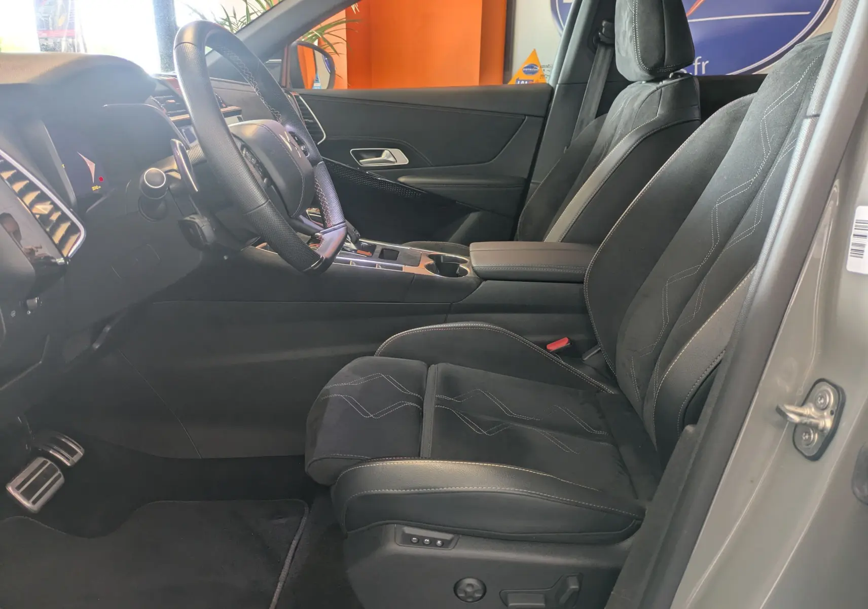 Vue intérieure côté conducteur du DS7 gris laque 2025, sièges en Alcantara noir avec coutures apparentes et console centrale moderne.