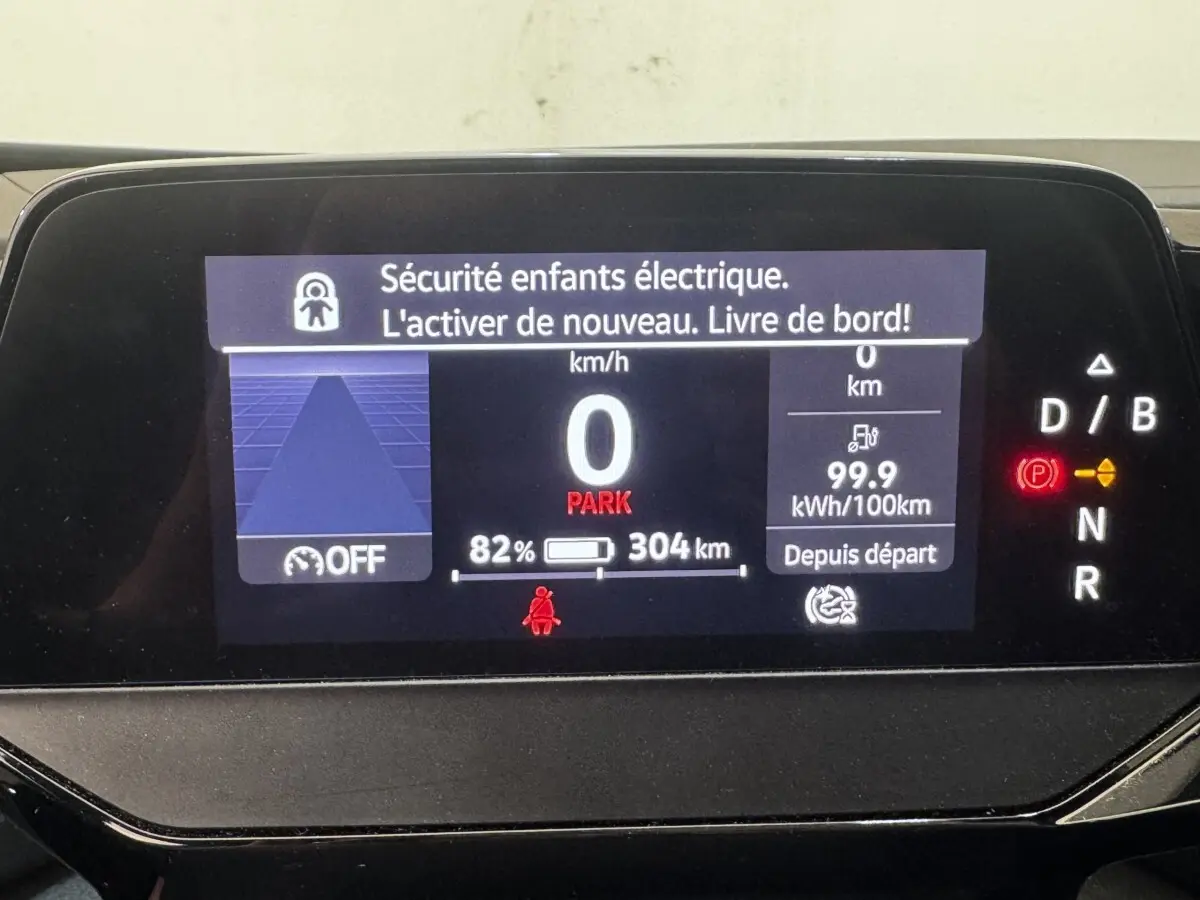 Affichage numérique du tableau de bord du Volkswagen ID.4 blanc, montrant vitesse, autonomie et alertes sécurité.